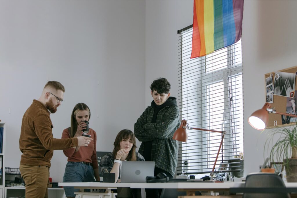 four people discussing something around a computer
