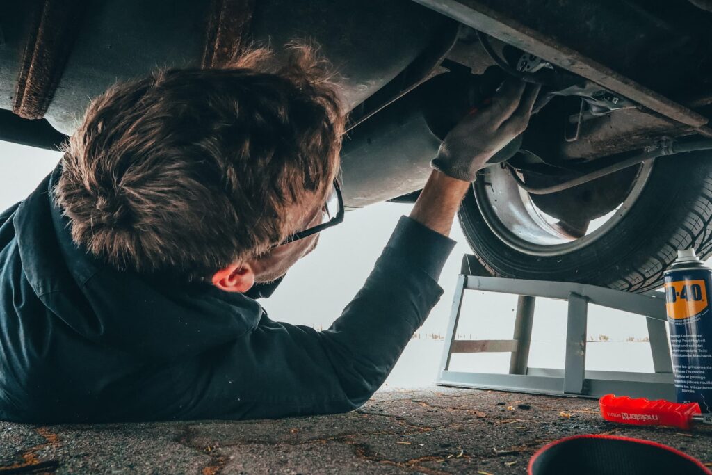 A man working underneath a car fixing the exhaust